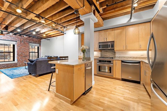 a kitchen with stainless steel appliances granite countertop a stove top oven a sink and a refrigerator