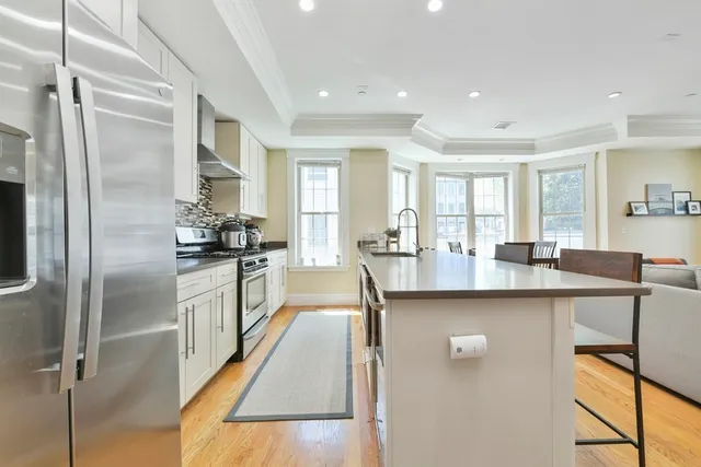 a kitchen with stainless steel appliances granite countertop a refrigerator a sink a stove and white cabinets