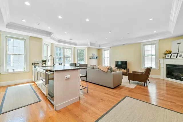 a living room with stainless steel appliances granite countertop furniture wooden floor and a window