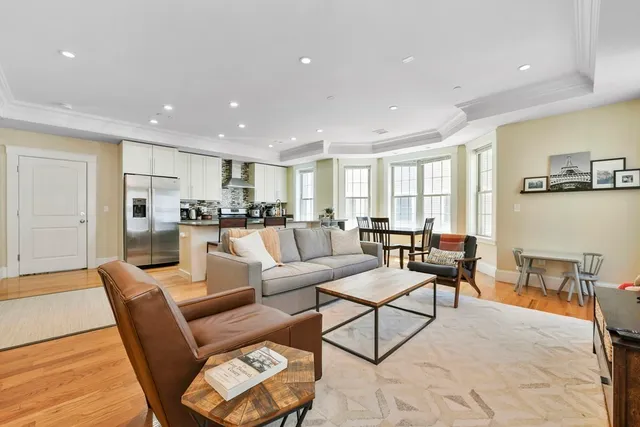 a living room with furniture wooden floor and kitchen view