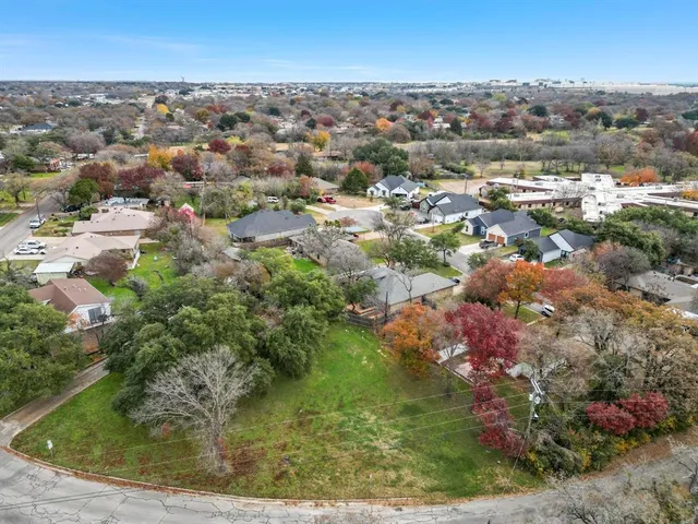 an aerial view of residential houses with outdoor space and trees