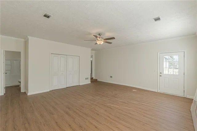 a view of a room with wooden floor and a ceiling fan