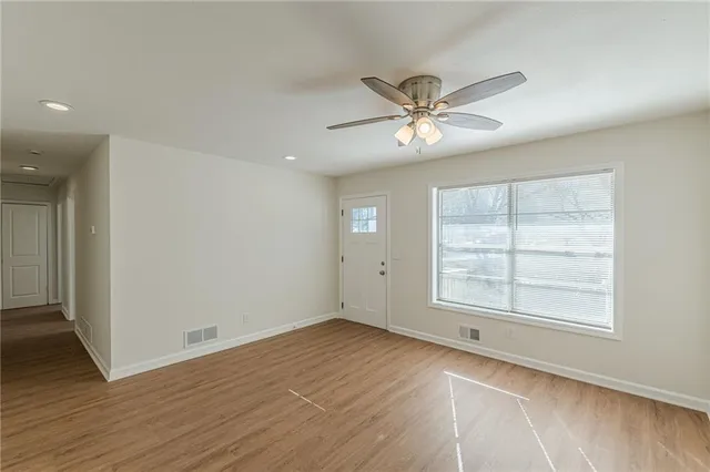 a view of empty room with wooden floor and fan