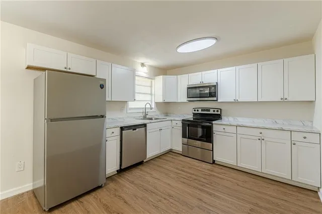 a kitchen with granite countertop a refrigerator stove and wooden floor