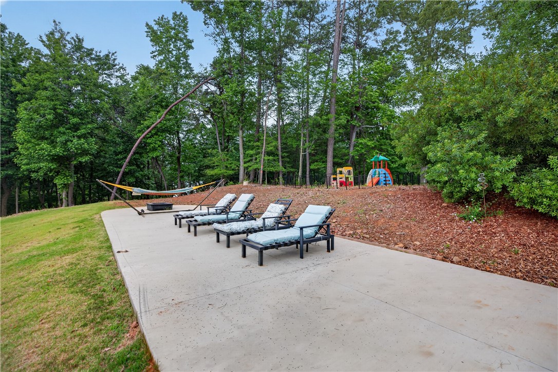206 James Hare Road Anderson, SC 29626 - Photo 11 of 37 A spacious concrete patio offers a serene outdoor escape with a hammock, lounge chairs, and a children's play area.