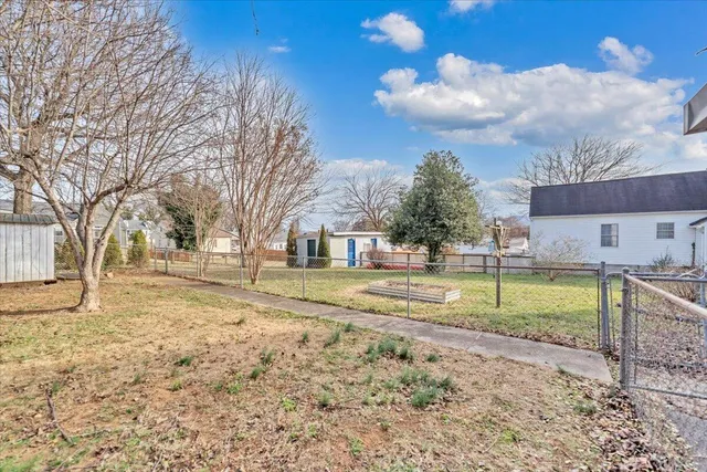 a backyard of a house with large trees and wooden fence