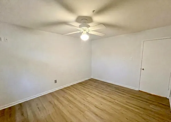 an empty room with wooden floor and fan