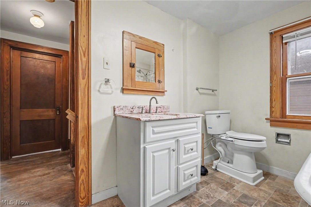 456 Delmar Avenue Akron, OH 44310 - Photo 17 of 27 Bathroom featuring a white vanity with a patterned countertop, a wood-framed medicine cabinet, and a window with wood trim
