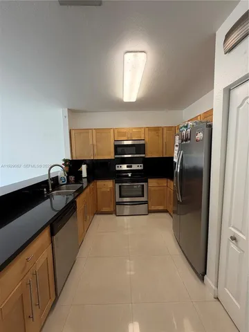 a kitchen with stainless steel appliances granite countertop a refrigerator and a sink