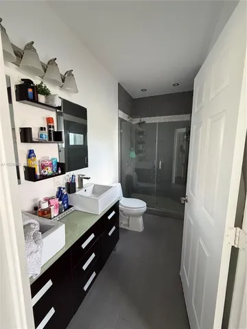 a bathroom with a granite countertop sink a toilet and shower