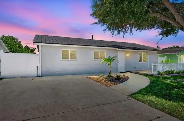 a backyard of a house with table and chairs potted plants and a large tree