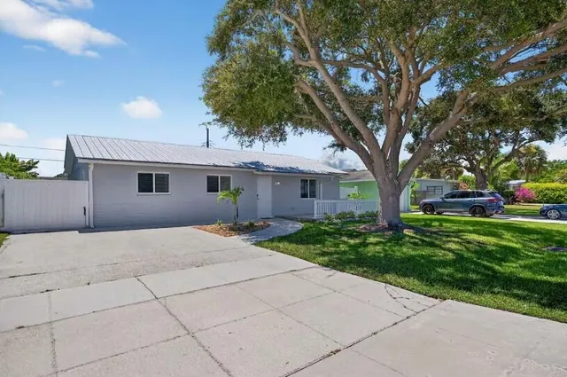 a front view of a house with a garden and trees