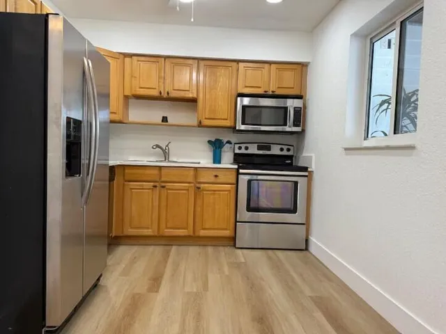 a kitchen with stainless steel appliances granite countertop a stove a sink and a refrigerator