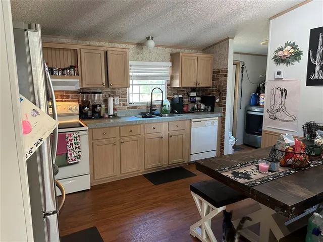 a kitchen with a stove a sink wooden floor and a refrigerator