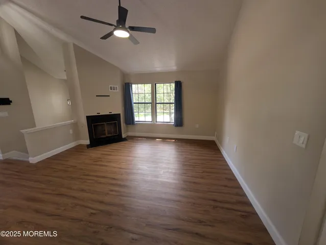 an empty room with wooden floor fireplace and windows