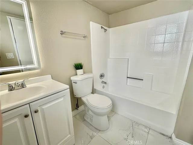 a view of an empty room with wooden floor and a bathroom
