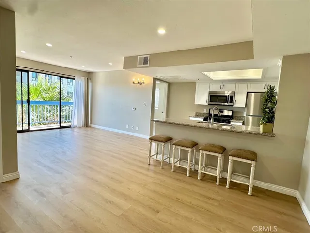 a open kitchen with kitchen island granite countertop a refrigerator cabinets and wooden floor