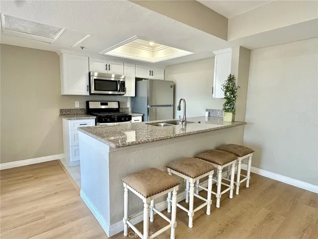 a kitchen with stainless steel appliances granite countertop a stove top oven a sink dishwasher a dining table and chairs with wooden floor