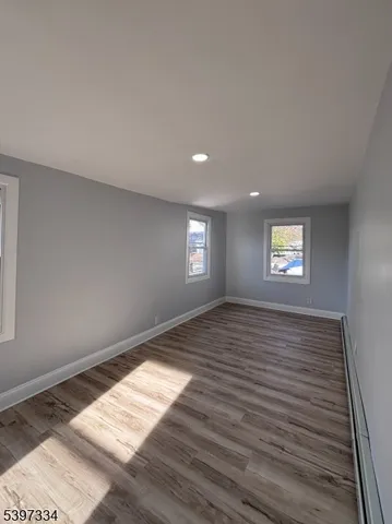 a view of an empty room and window and wooden floor