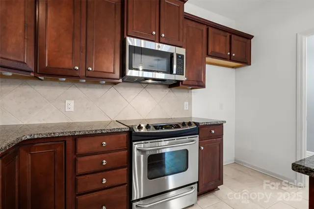 a kitchen with stainless steel appliances granite countertop wooden cabinets and a stove top oven