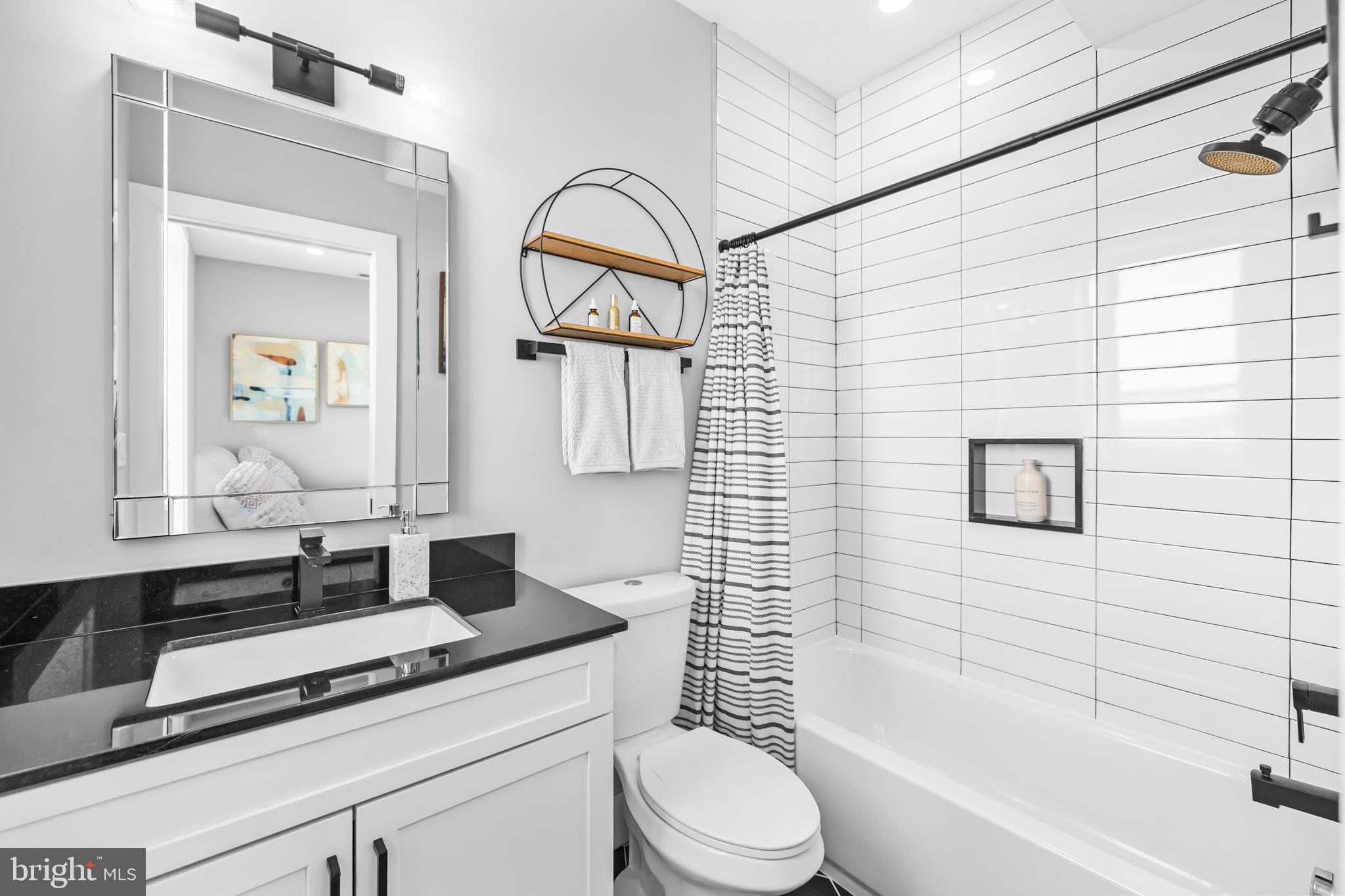 1915 H Street Northeast, Unit PH1 Washington, DC 20002 - Photo 3 of 21 a bathroom with a granite countertop sink toilet a mirror and bathtub