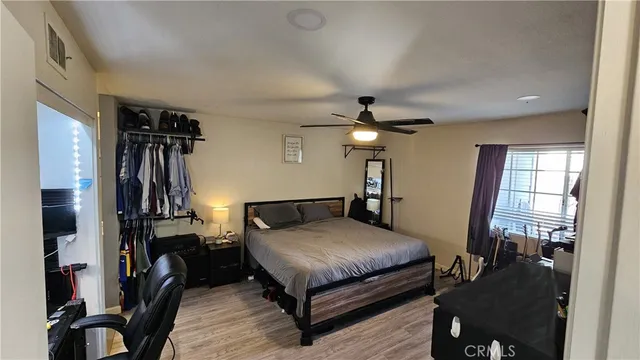 a bedroom with a bed and dresser with wooden floor