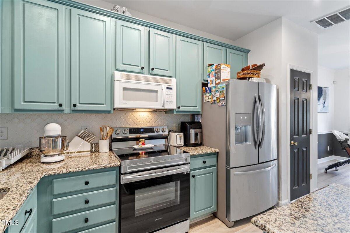 5730 Clearbay Lane Raleigh, NC 27612 - Photo 13 of 32 a kitchen with refrigerator a stove a washer and dryer