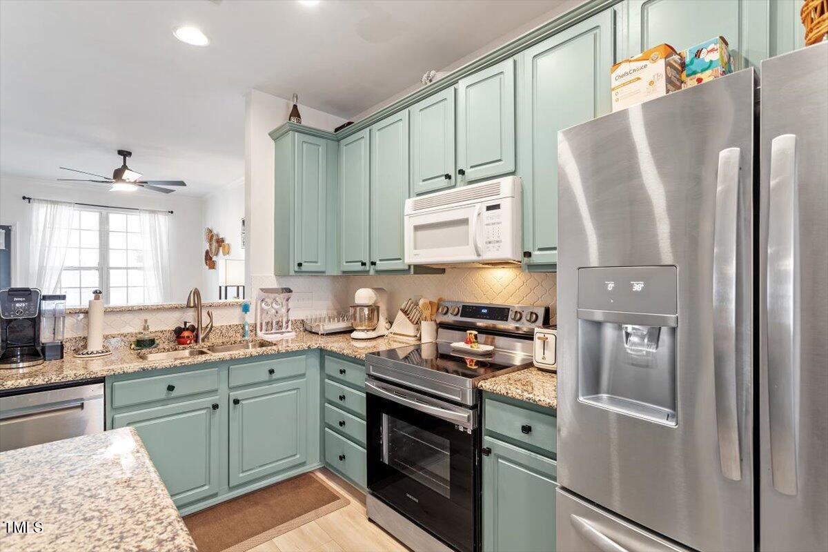 5730 Clearbay Lane Raleigh, NC 27612 - Photo 10 of 32 a kitchen with stainless steel appliances a refrigerator sink and cabinets