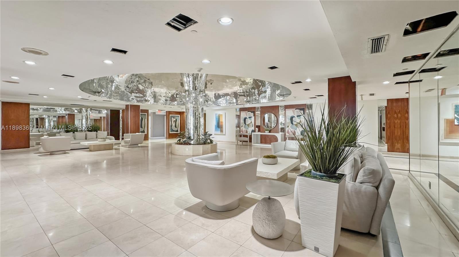 2655 Collins Avenue, Unit 1502 Miami Beach, FL 33140 - Photo 11 of 11 a living room with lots of furniture and a chandelier