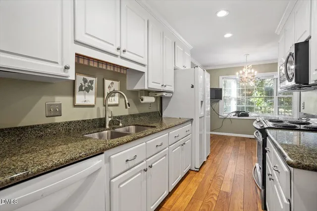 a kitchen with stainless steel appliances granite countertop a sink a stove and a wooden floors