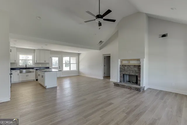 a view of empty room with wooden floor and a kitchen