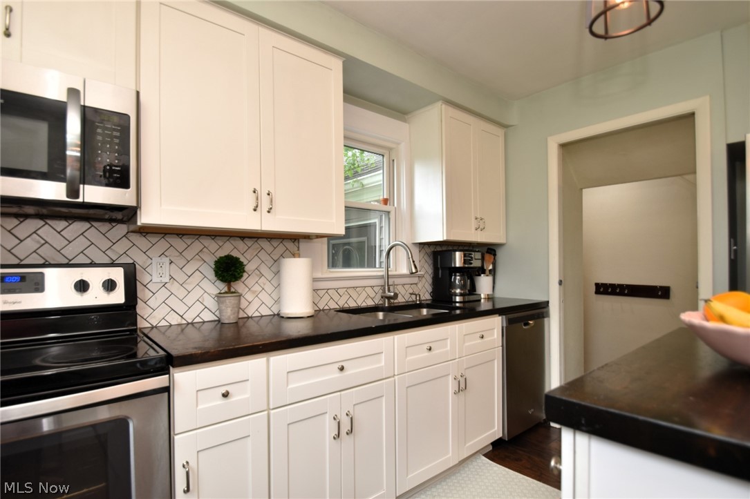1174 Haverston Road Cleveland, OH 44124 - Photo 11 of 21 Kitchen featuring dark hardwood / wood-style flooring, backsplash, sink, white cabinetry, and appliances with stainless steel finishes