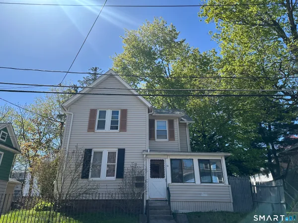 a front view of a house with a tree