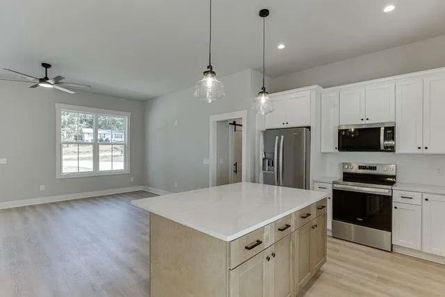 a kitchen with stainless steel appliances a sink a stove a refrigerator cabinets and wooden floor