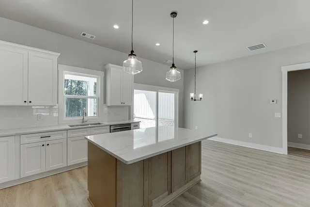 a kitchen with granite countertop a sink cabinets and wooden floor