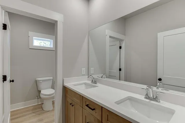 a bathroom with a granite countertop sink a toilet and a mirror