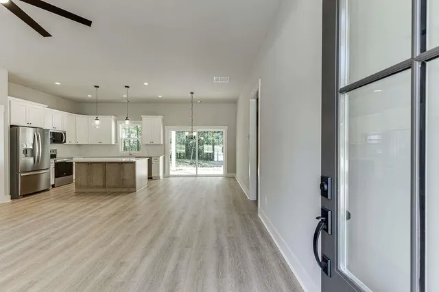 a view of kitchen with stainless steel appliances refrigerator wooden floor and window