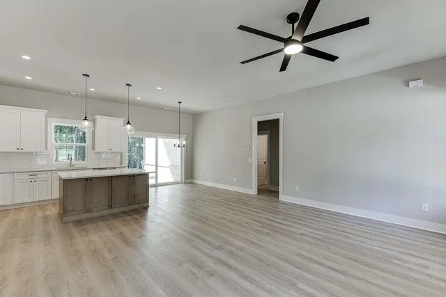 a large kitchen with cabinets wooden floor and a window