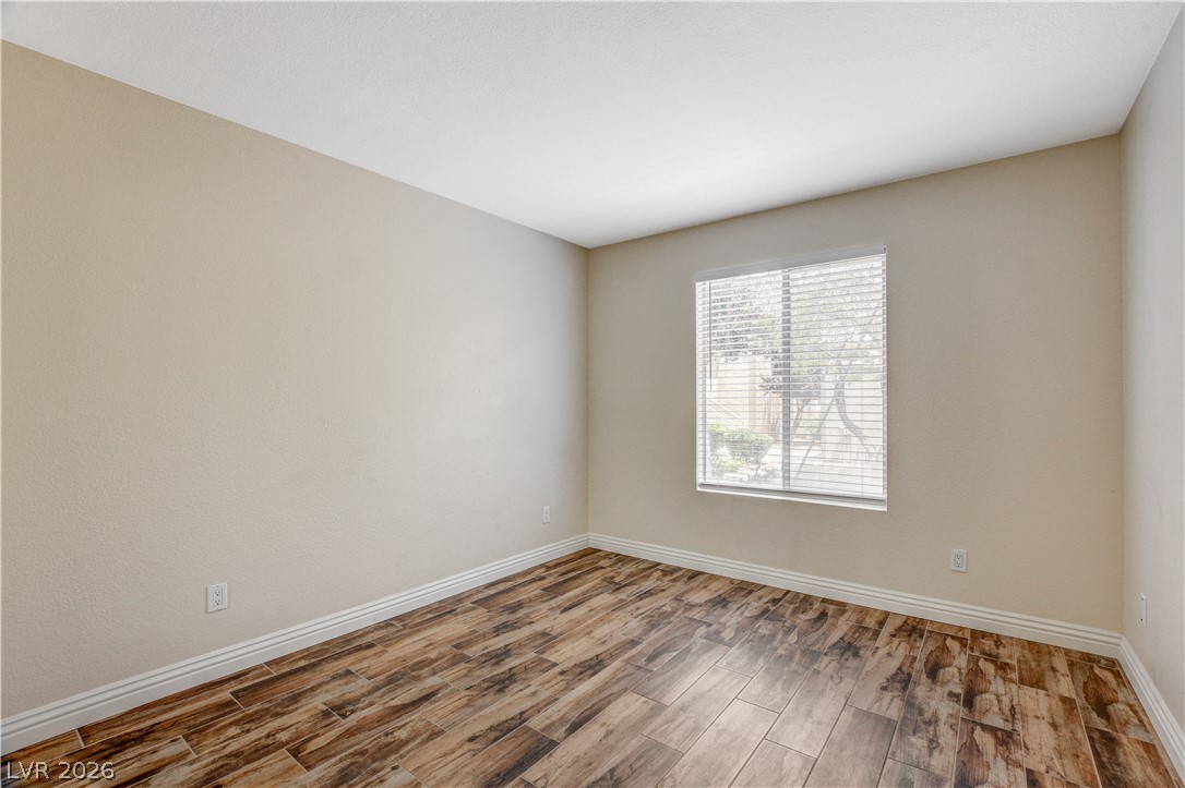 7200 West Pirates Cove Road, Unit 1026 Las Vegas, NV 89145 - Photo 18 of 35 This spacious room features ample natural light and rich wood flooring, offering versatile design possibilities.