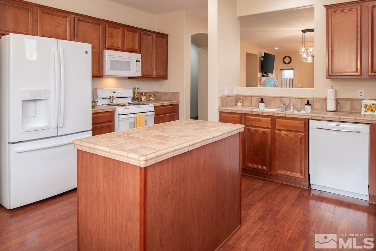 10417 Chadwell Drive Reno, NV 89521 - Photo 11 of 40 a kitchen with stainless steel appliances kitchen island wooden cabinets a sink and a refrigerator