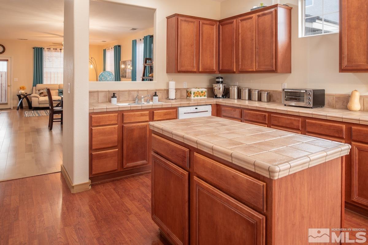 10417 Chadwell Drive Reno, NV 89521 - Photo 6 of 40 a kitchen with stainless steel appliances granite countertop wooden cabinets a sink and dishwasher a stove with wooden floor