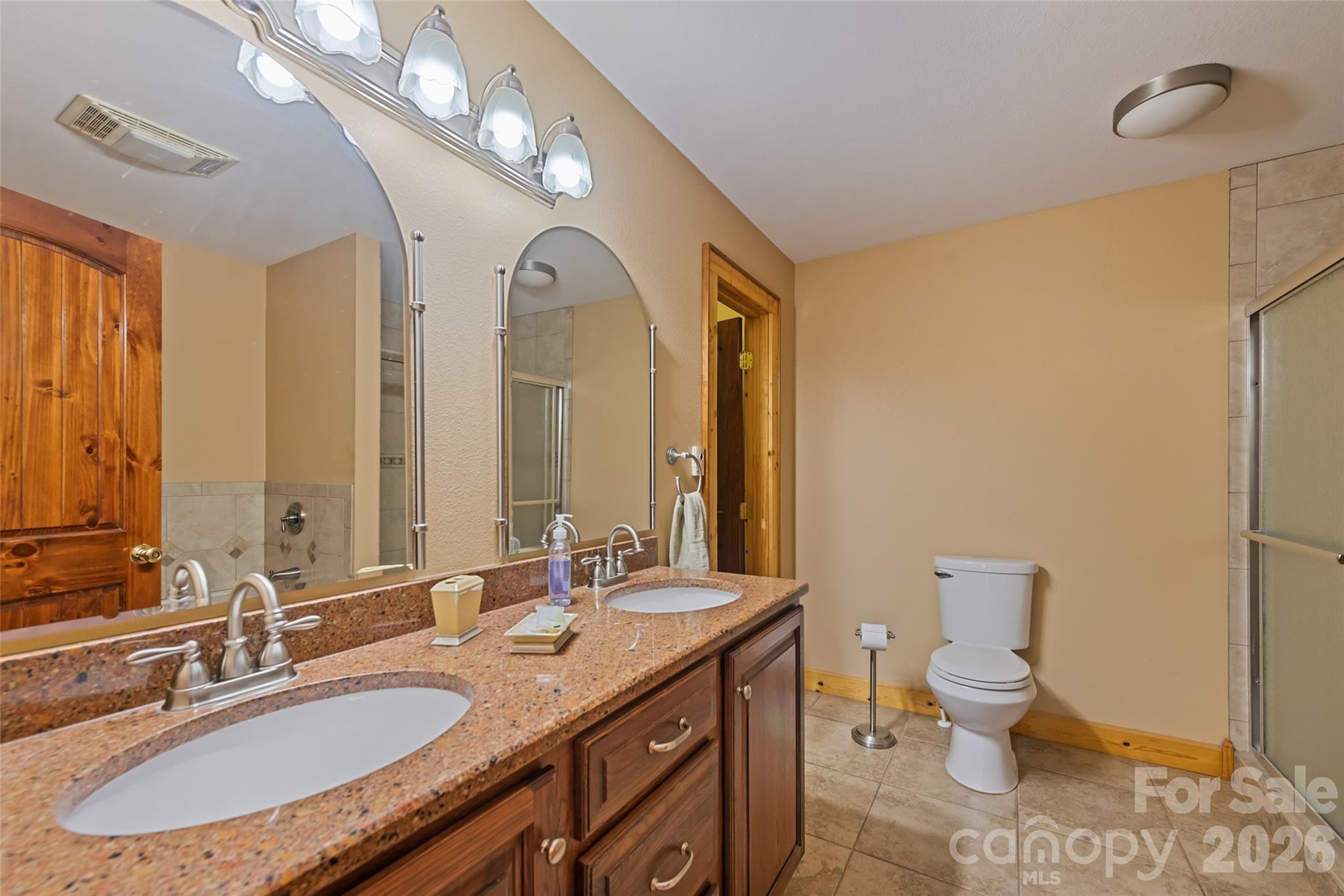 235 Soaring Eagle Road Bryson City, NC 28713 - Photo 23 of 43 a bathroom with a granite countertop double vanity sink a mirror and a toilet