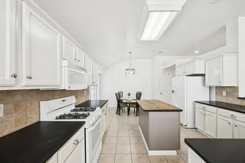 a kitchen with a sink a stove a refrigerator and white cabinets