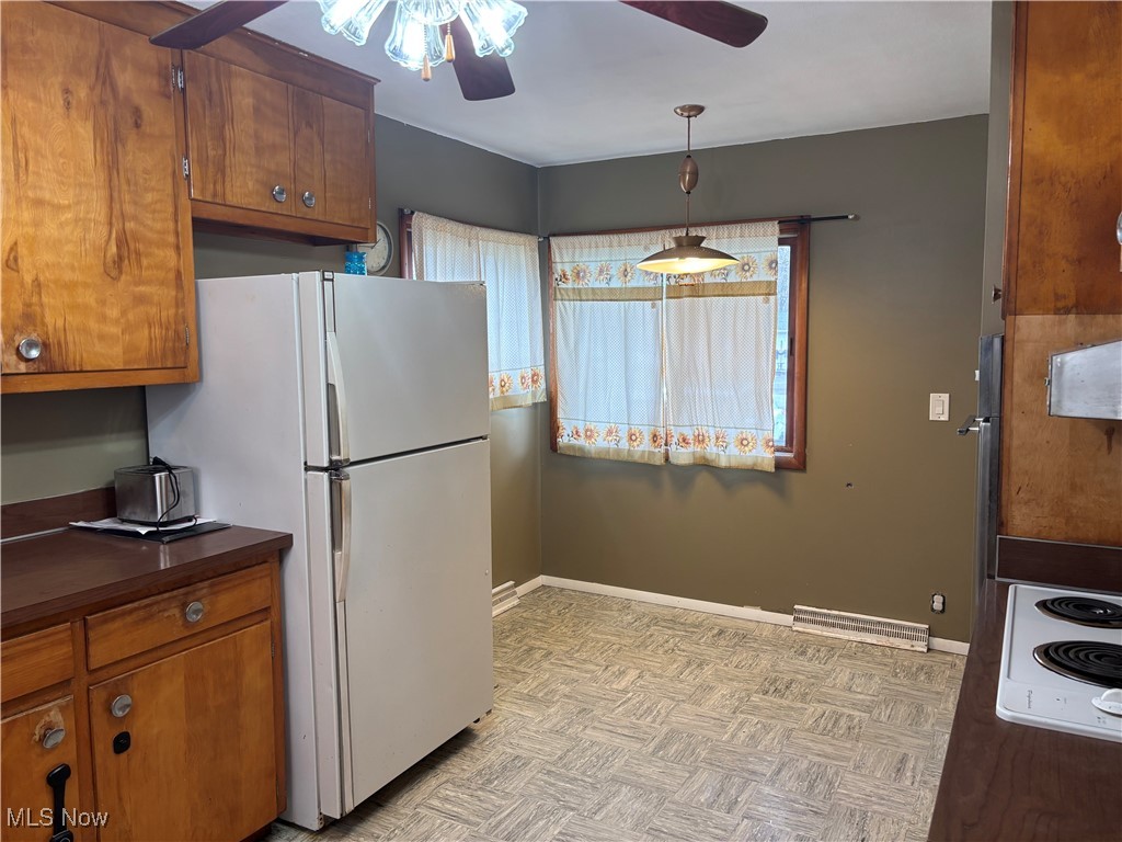 Kitchen featuring a ceiling fan, brown wood cabinetry, and white appliances
