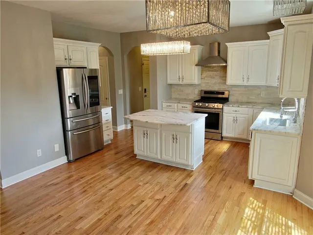 a kitchen with stainless steel appliances a sink a stove a refrigerator and wooden floor
