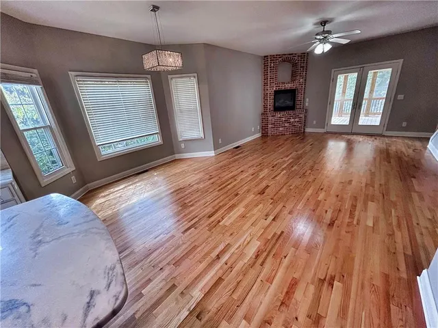 a view of an empty room with window and wooden floor