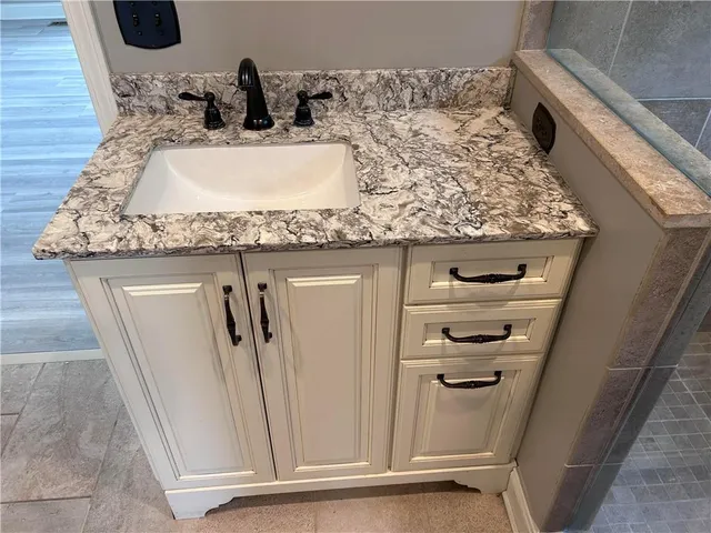 a bathroom with a granite countertop sink and a mirror