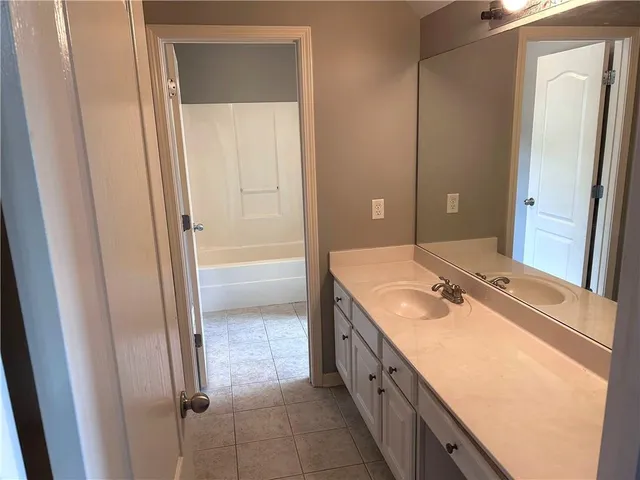 a bathroom with a granite countertop sink a mirror and a shower