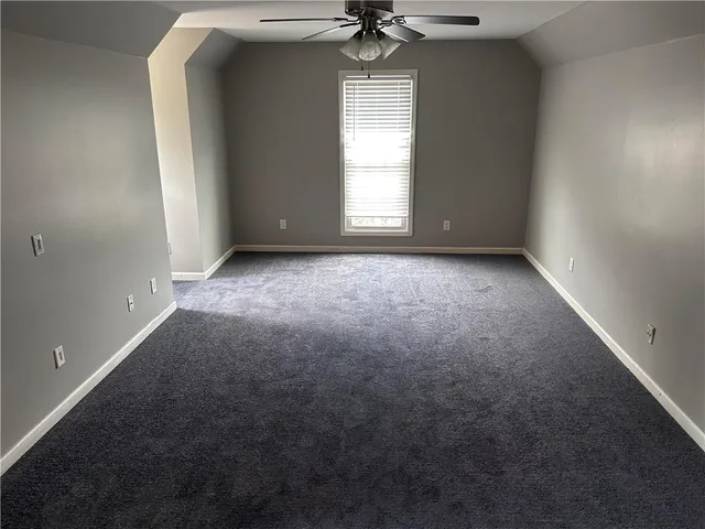 an empty room with a window and a chandelier fan