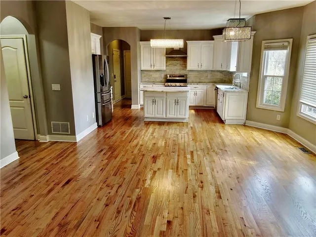 a view of a kitchen with wooden floor and stainless steel appliances